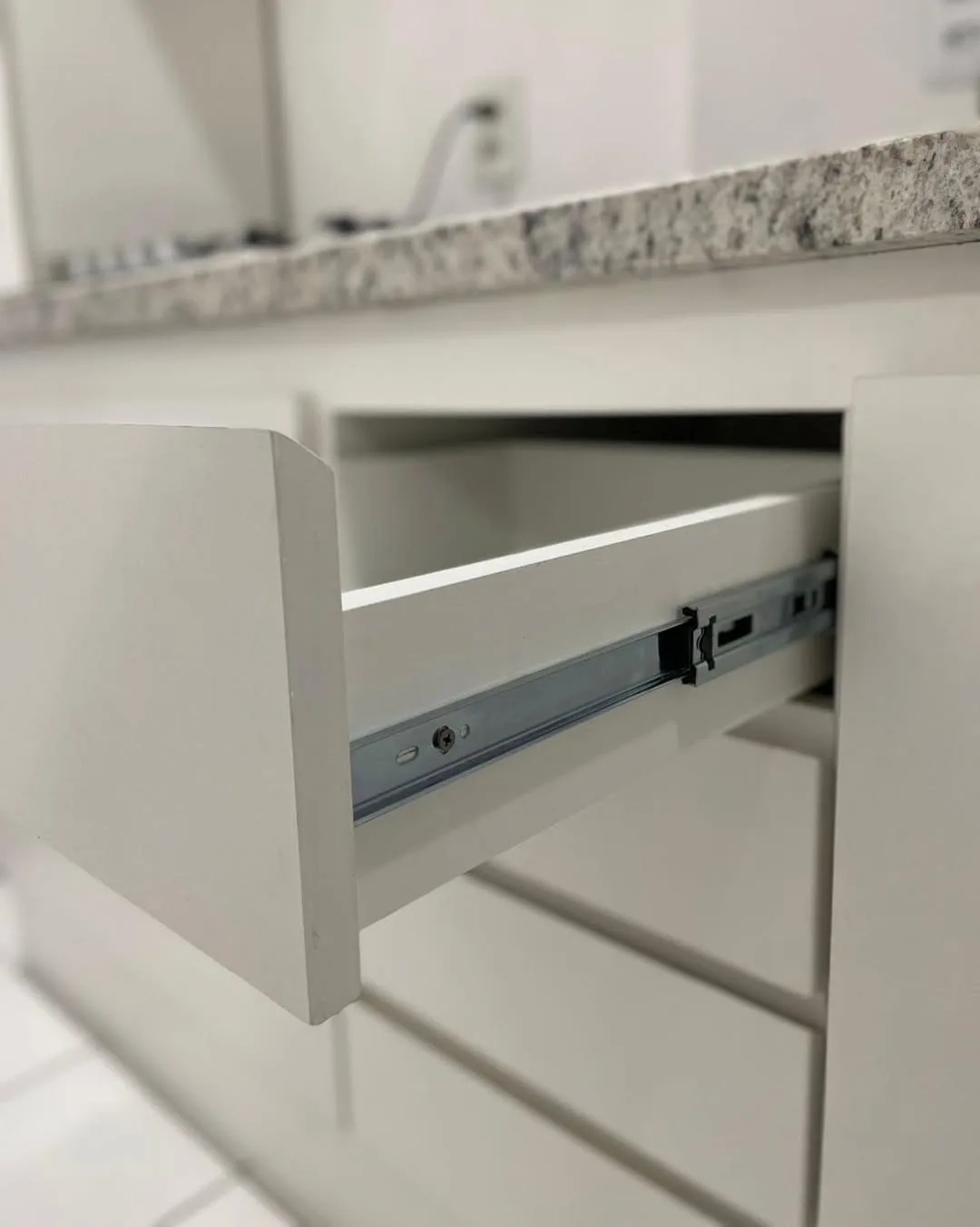 Detalhe de gaveta com corrediça e tampo de granito