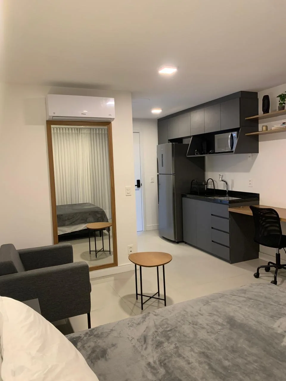 Studio com bancada de home office e painel de TV